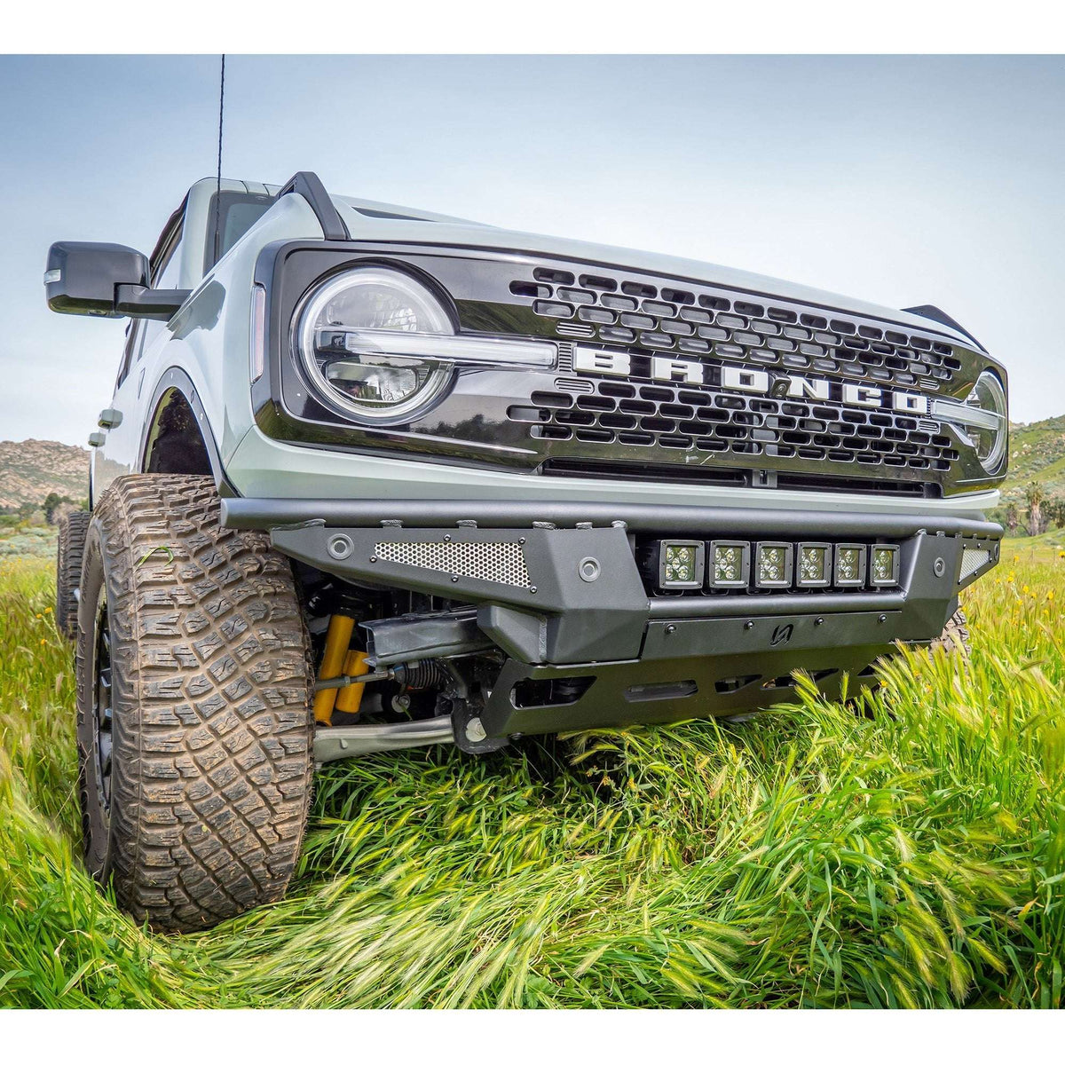 Turn Offroad Baja front bumper and skid plate installed on gray Ford Bronco, front three-quarter close-up view in grass field