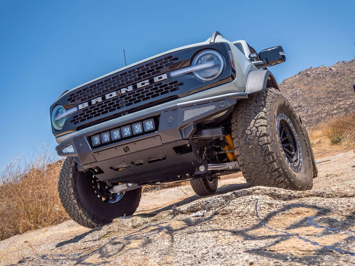 Turn Offroad Baja front bumper and skid plate installed on gray Ford Bronco, front three-quarter view on rocky terrain