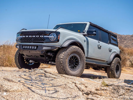 Turn Offroad Baja front bumper and skid plate installed on gray Ford Bronco with soft top down, side profile view on rocky terrain