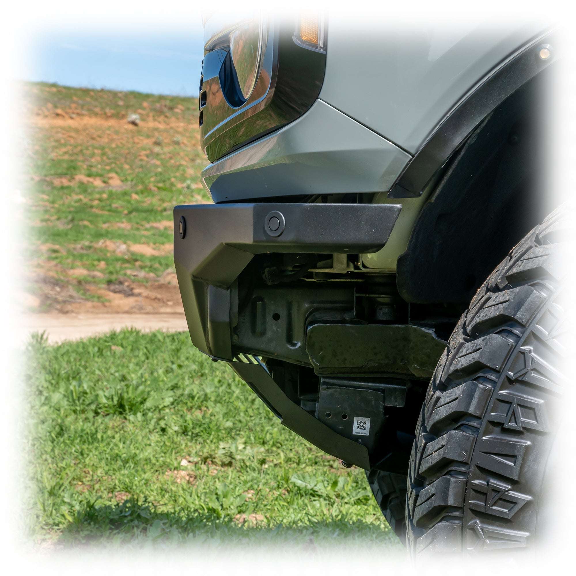Turn Offroad Hyperlyte front bumper installed on olive green Ford Bronco, close-up showing bumper corner and wheel in grass field