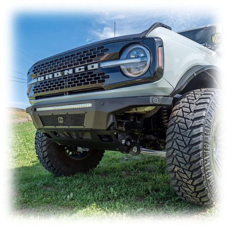 Turn Offroad Hyperlyte front bumper installed on white Ford Bronco with KC light pods, front three-quarter view on hillside