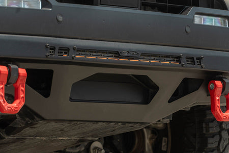 DV8 Offroad front bumper compatible with FBBO-01 fairlead cover plate, close-up showing red D-ring recovery shackle mount and skid plate