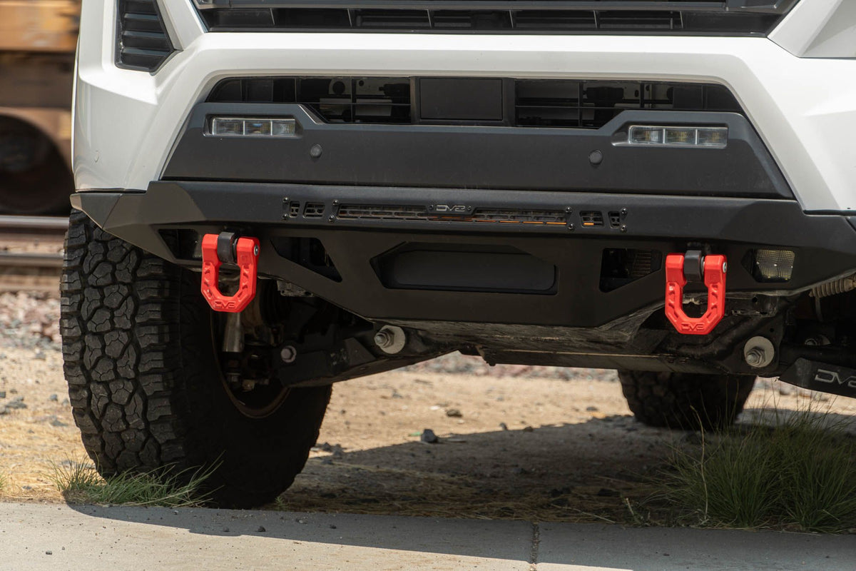 DV8 Offroad front bumper compatible with FBBO-01 fairlead cover plate, straight-on low angle view showing full width and dual red D-rings