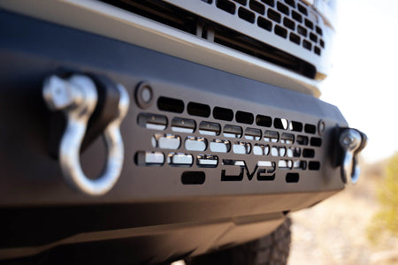 DV8 Offroad OE Plus Series front bumper installed on silver Ford Bronco, close-up showing shackle mount and honeycomb grille
