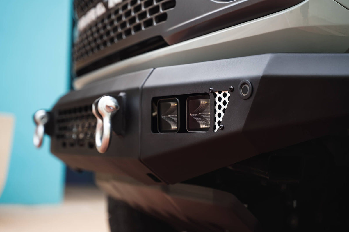 DV8 Offroad OE Plus Series front bumper installed on dark Ford Bronco, close-up showing shackle mount and square light pods