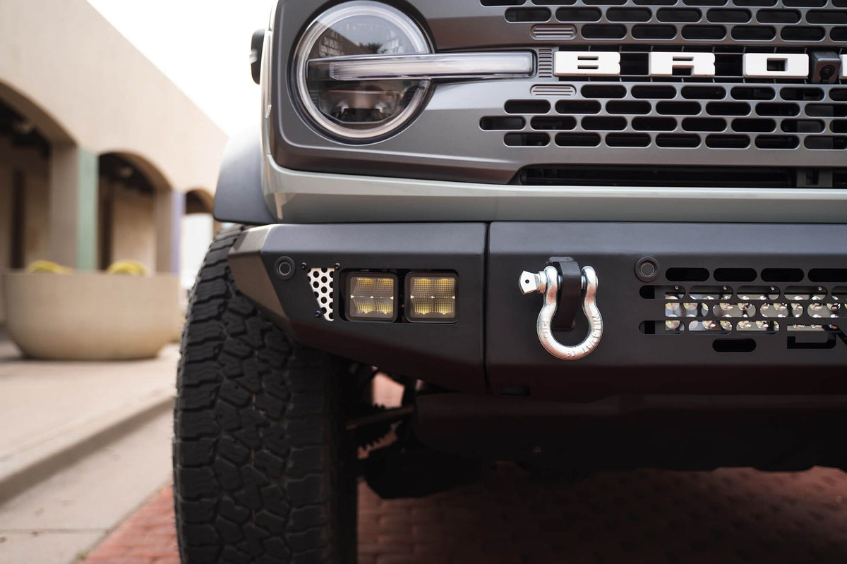 DV8 Offroad OE Plus Series front bumper installed on black Ford Bronco, close-up showing honeycomb grille and D-ring shackle mount