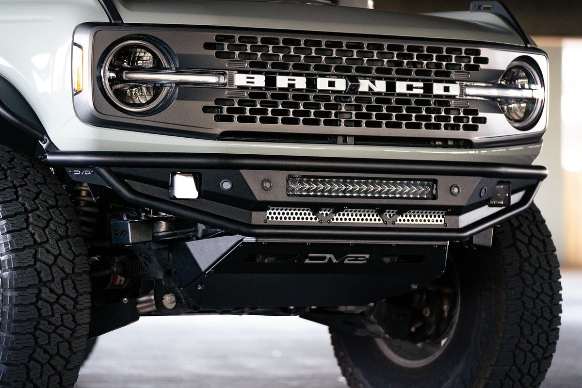 DV8 Offroad Competition Series front bumper installed on dark Ford Bronco, close-up showing bumper corner and wheel in parking garage, alternate angle