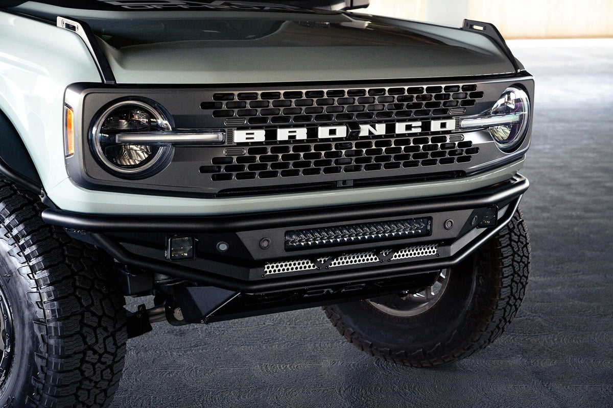 DV8 Offroad Competition Series front bumper installed on light-colored Ford Bronco, close-up showing grille and bumper in parking garage