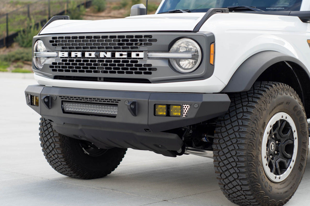 DV8 Offroad OE Plus Series V2 front bumper installed on white Ford Bronco, close-up front view on hillside