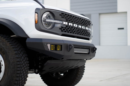 DV8 Offroad OE Plus Series V2 front bumper installed on white Ford Bronco, close-up front view in urban lot