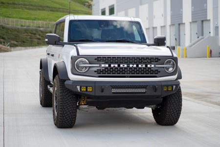 DV8 Offroad OE Plus Series V2 front bumper installed on white Ford Bronco, straight-on front view in industrial lot