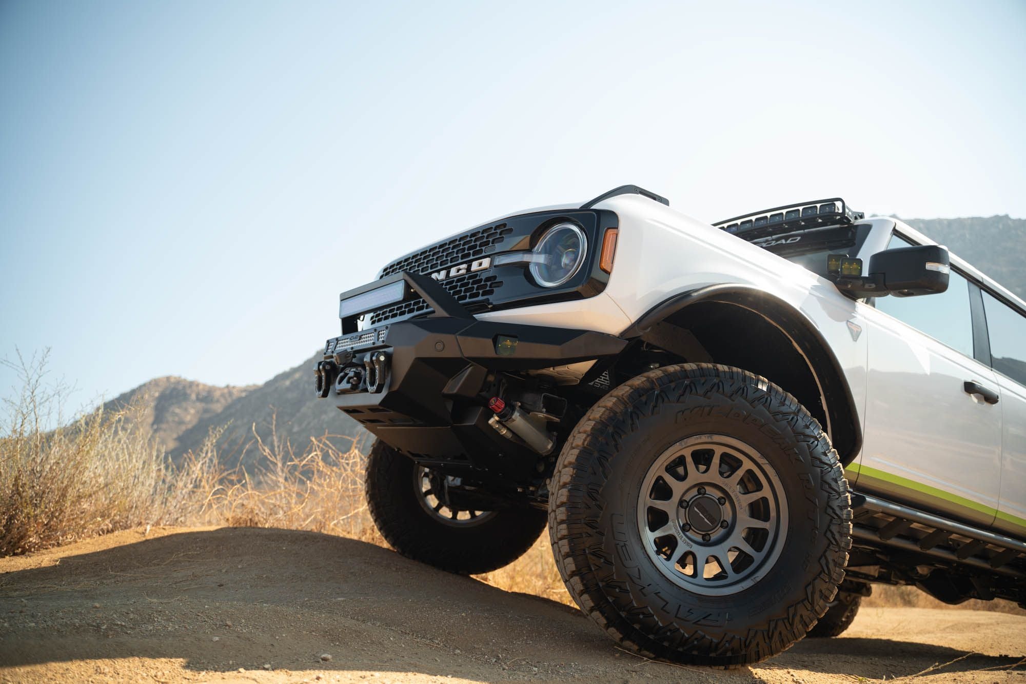 DV8 Offroad FBBR-07 MTO V2 front bumper installed on white Ford Bronco – low angle front view desert