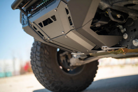 DV8 Offroad Tube Series front bumper installed on Ford Bronco, underside close-up showing skid plate