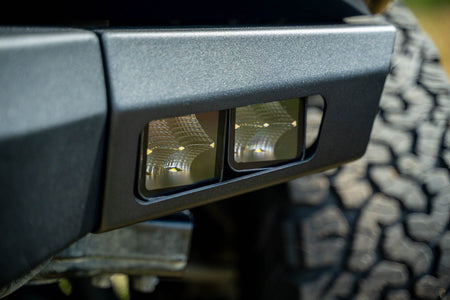 DV8 Offroad Spec Series winch front bumper installed on black Ford Bronco Raptor, close-up showing bumper corner and wheel