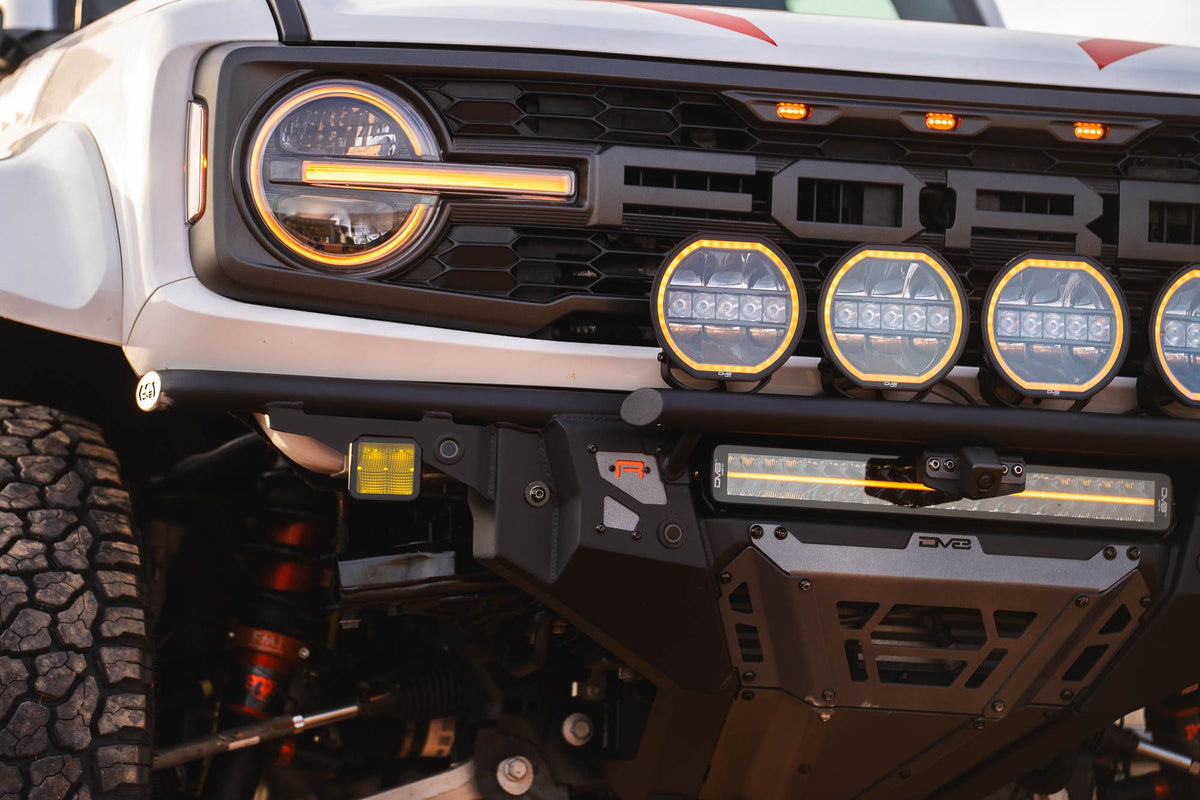 DV8 Offroad Tube Series front bumper installed on white Ford Bronco Raptor, close-up showing headlight, grille, and light pods
