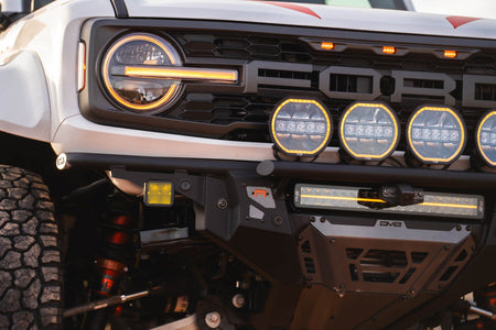 DV8 Offroad Tube Series front bumper installed on white Ford Bronco Raptor, close-up showing headlight, grille, and light pods
