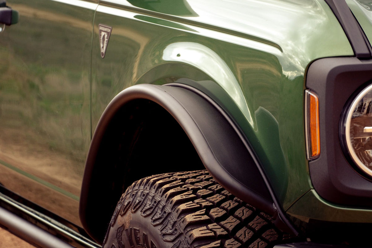 DV8 Offroad tube fender flares installed on green 4-door Ford Bronco, close-up front fender and headlight