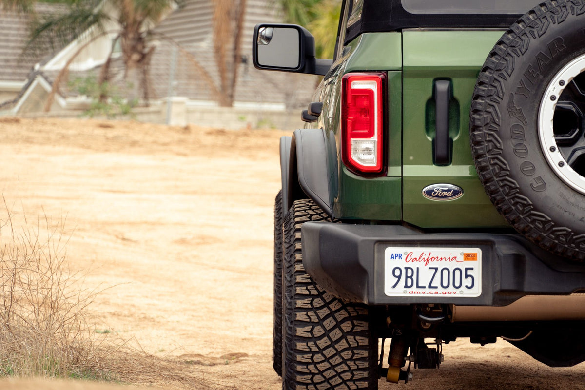 DV8 Offroad tube fender flares installed on green 4-door Ford Bronco, close-up rear quarter with spare tire