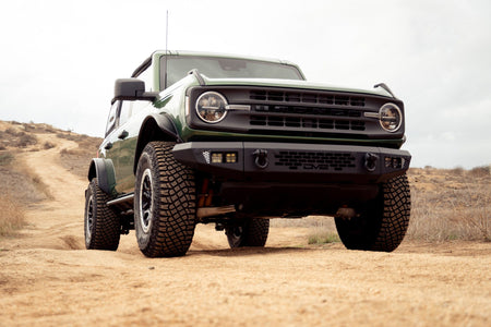 DV8 Offroad tube fender flares installed on green 4-door Ford Bronco, front view on dirt trail