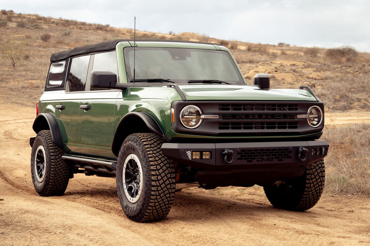 DV8 Offroad tube fender flares installed on green 4-door Ford Bronco, front three-quarter view on hillside trail