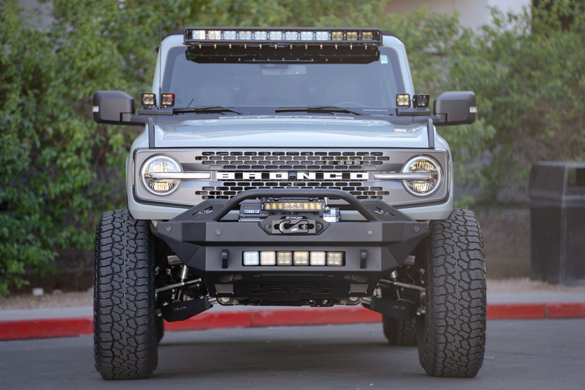 DV8 Offroad fender flare delete installed on Ford Bronco with light bar and winch bumper, front view at dusk