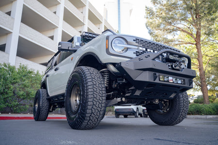 DV8 Offroad fender flare delete installed on lifted Ford Bronco, front three-quarter view in parking garage