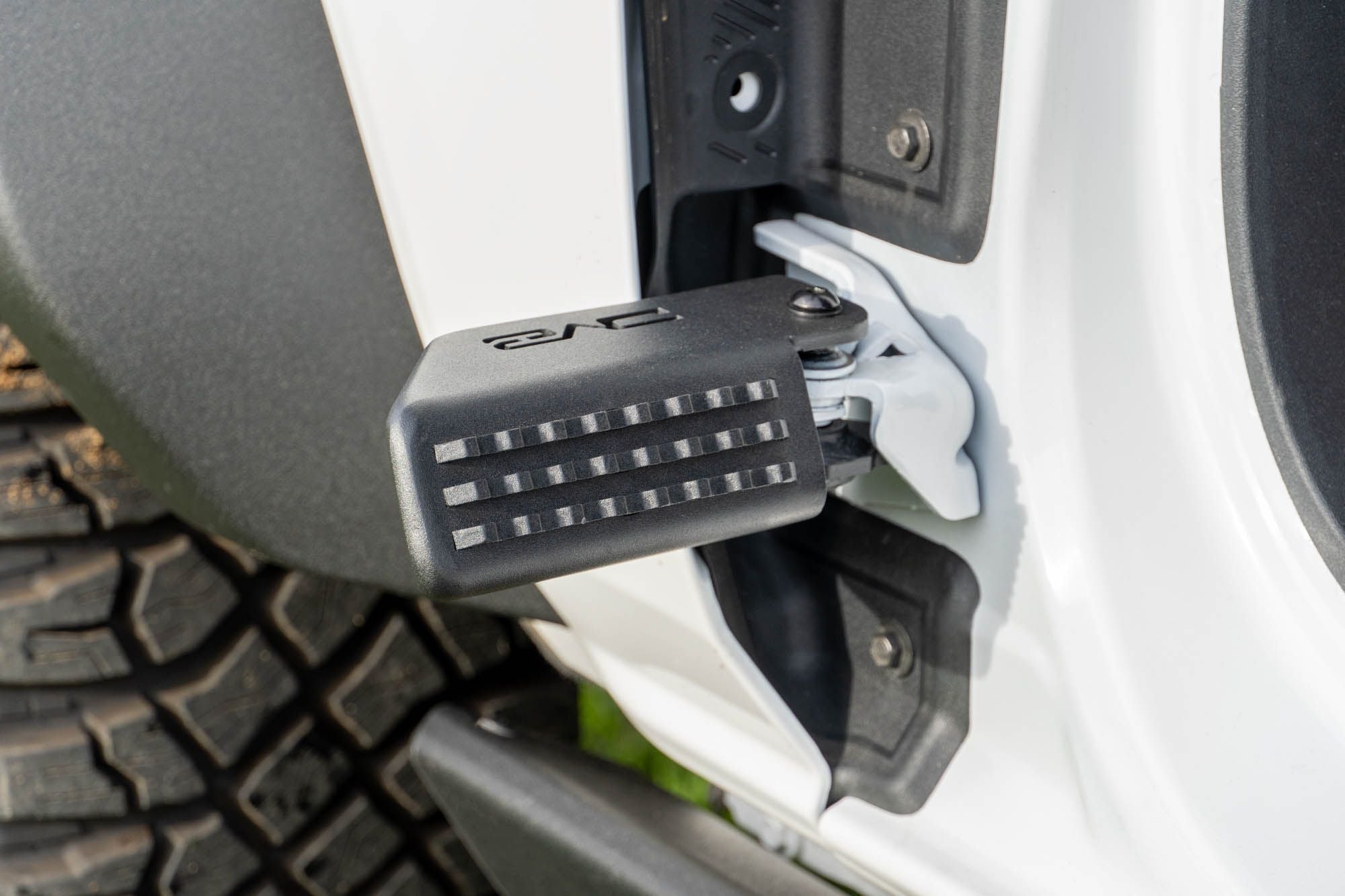 DV8 Offroad foot peg installed on 2021-2026 Ford Bronco door hinge detail view showing peg angle and grip surface