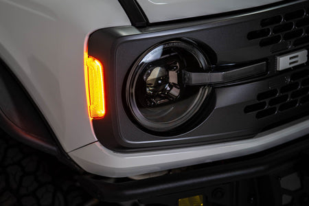 DV8 Offroad Black Series LED headlight installed on white Ford Bronco, close-up showing red marker light and amber DRL
