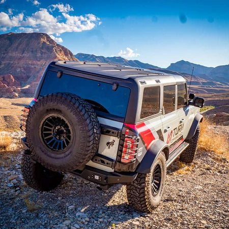Turn Offroad TR10 hard top installed on dark 4-door Ford Bronco, rear three-quarter view on rocky desert terrain