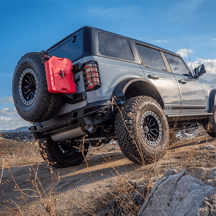 Turn Offroad TR10 hard top installed on gray 4-door Ford Bronco, rear three-quarter view with fuel canister on rocky trail