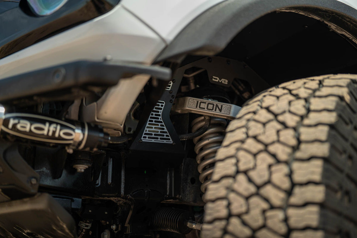 DV8 Offroad front inner fenders installed on white Ford Bronco, close-up wheel well showing DV8 logo and Icon branding