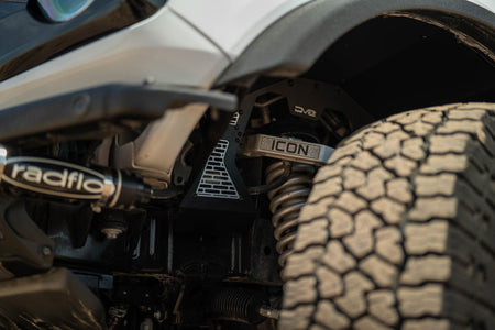 DV8 Offroad front inner fenders installed on white Ford Bronco, close-up wheel well showing DV8 logo and Icon branding