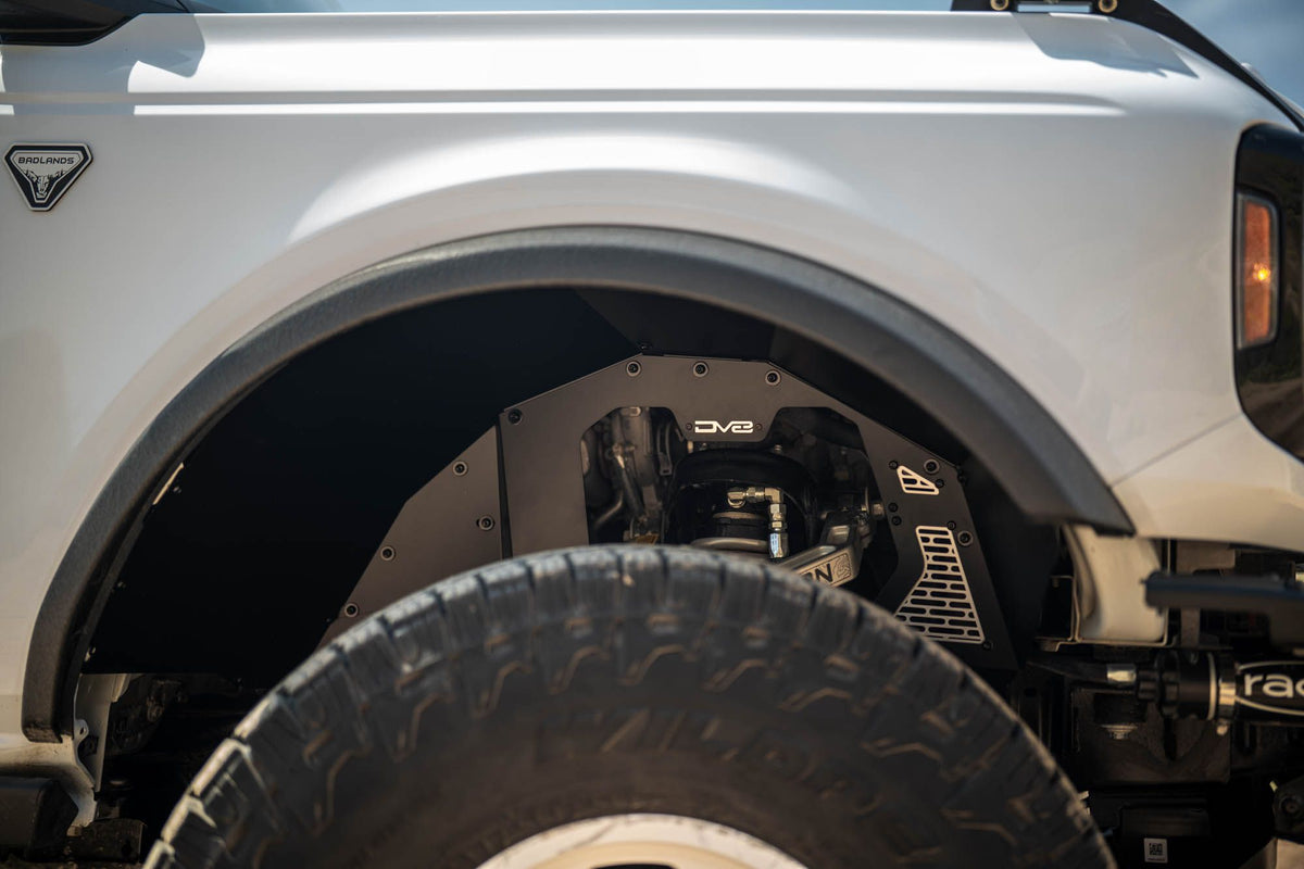 DV8 Offroad front inner fenders installed on white Ford Bronco, close-up showing fender and tire with coilover shock