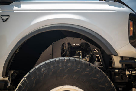 DV8 Offroad front inner fenders installed on white Ford Bronco, close-up showing fender and tire with coilover shock