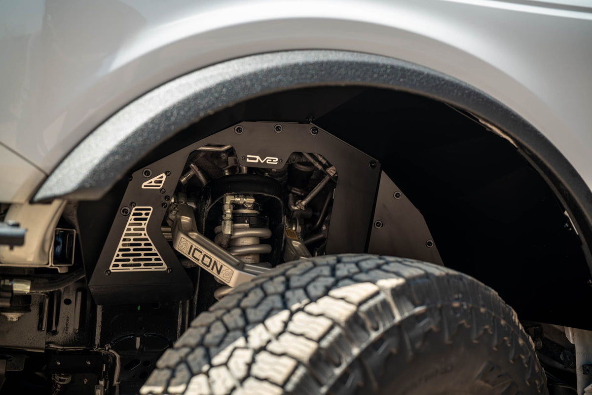 DV8 Offroad front inner fenders installed on Ford Bronco, close-up wheel well interior showing mesh panel and Icon badge