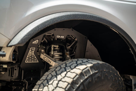 DV8 Offroad front inner fenders installed on Ford Bronco, close-up wheel well interior showing mesh panel and Icon badge