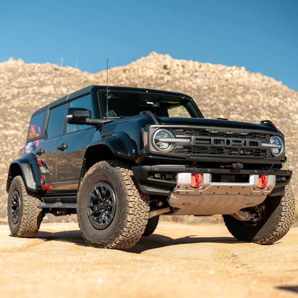 DV8 Offroad LBBR-10 Tube Push Bar installed on black Ford Bronco 4-door with red recovery points – front three-quarter view desert terrain