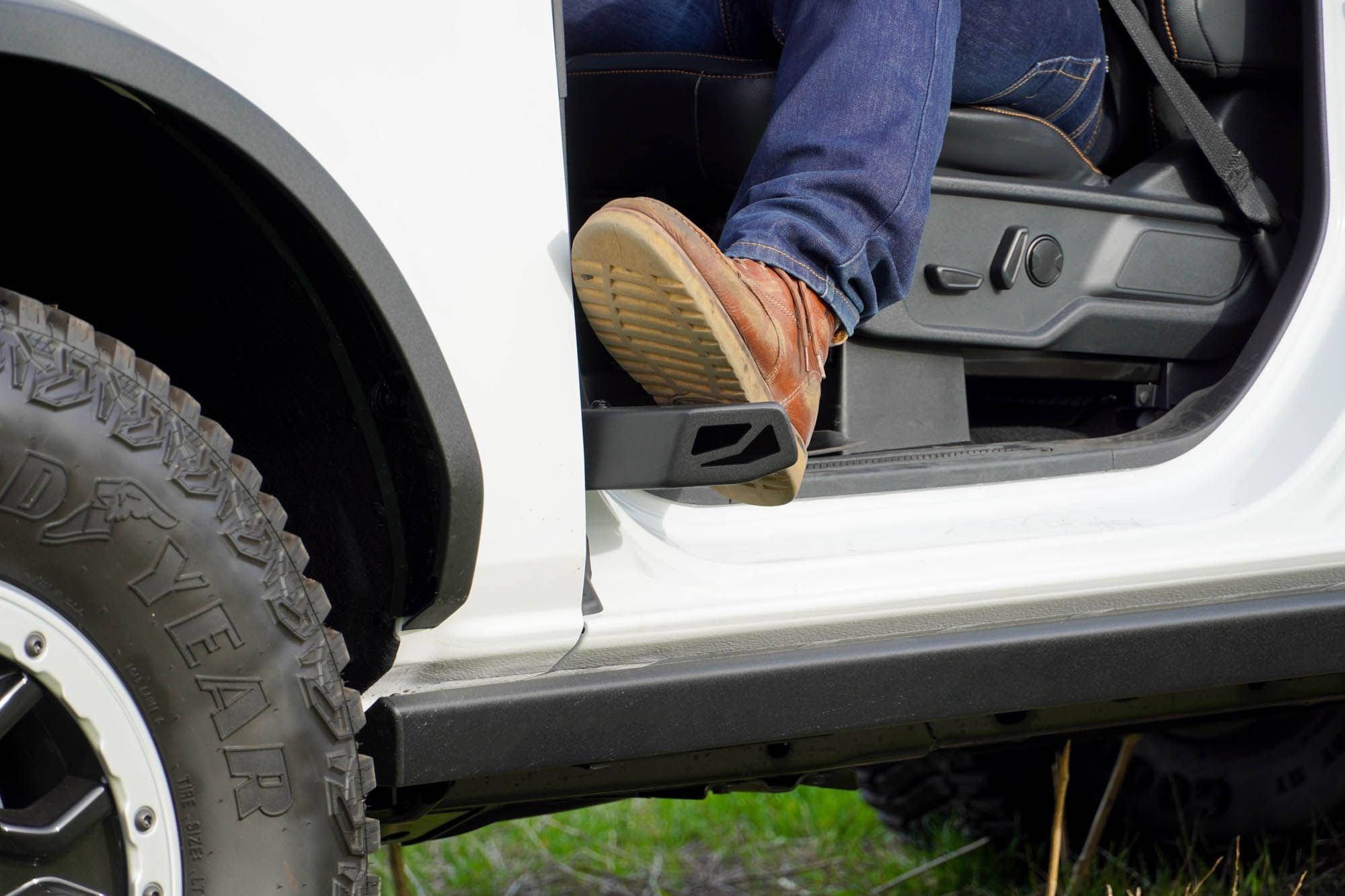 DV8 Offroad foot peg in use on 2021-2026 Ford Bronco side view showing rider stepping onto door hinge peg