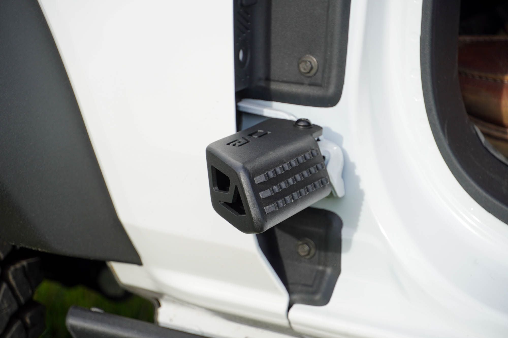 DV8 Offroad foot peg installed on 2021-2026 Ford Bronco door hinge close-up showing bracket mounting position
