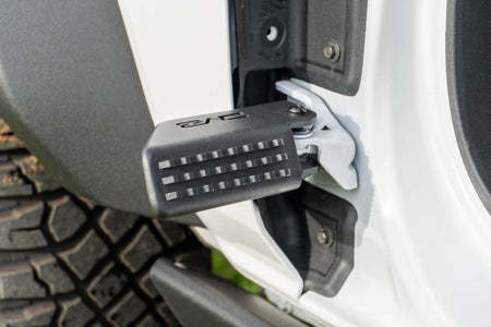 DV8 Offroad foot peg installed on 2021-2026 Ford Bronco door hinge detail view showing peg angle and grip surface
