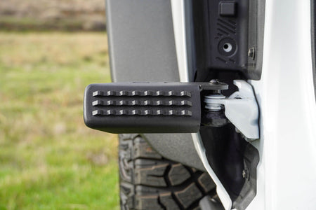 DV8 Offroad foot peg installed on 2021-2026 Ford Bronco showing peg position mounted on front door hinge