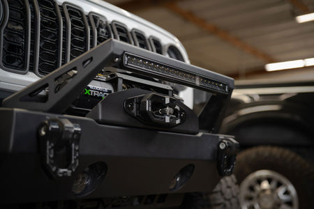 DV8 Offroad Xtract fairlead installed on Jeep front bumper with LED light bar, warehouse setting