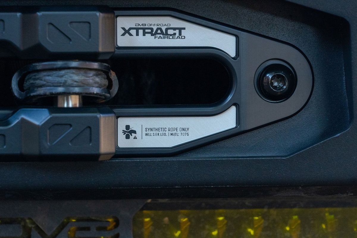 DV8 Offroad Xtract fairlead installed on textured dark bumper, close-up with amber accent lighting