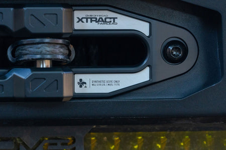 DV8 Offroad Xtract fairlead installed on textured dark bumper, close-up with amber accent lighting
